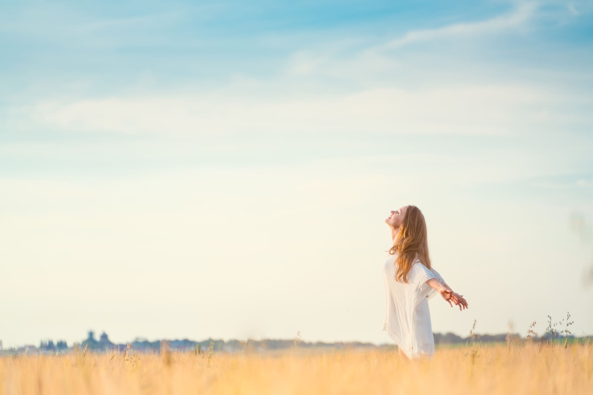 Mujer disfrutando de la naturaleza con los brazos extendidos, sintiendo libertad y plenitud.